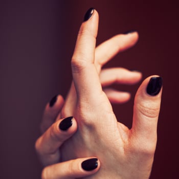 Sleek woman's fingernails painted in black nail polish