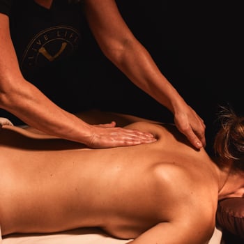 Woman receiving a deep tissue massage with a licensed massage therapist working on her back.