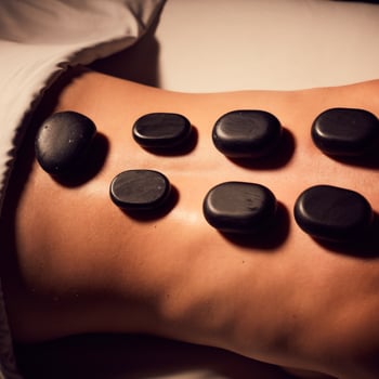 Close-up of a woman's back with seven hot basalt stones during a Hot Rock Massage.