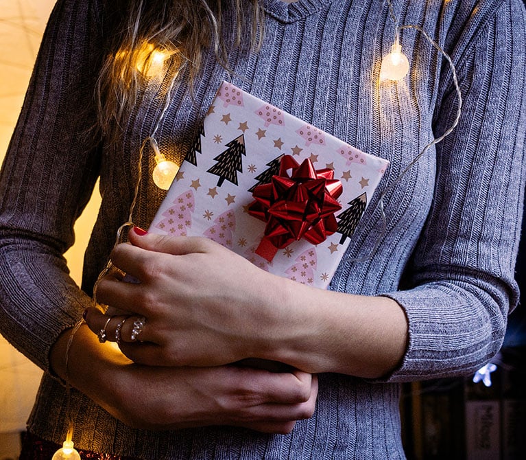 Woman holding a wrapped gift in front of a