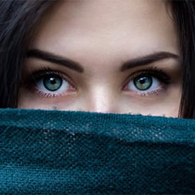 Woman with blue eyes and smooth forehead peeking out from behind her sweater.