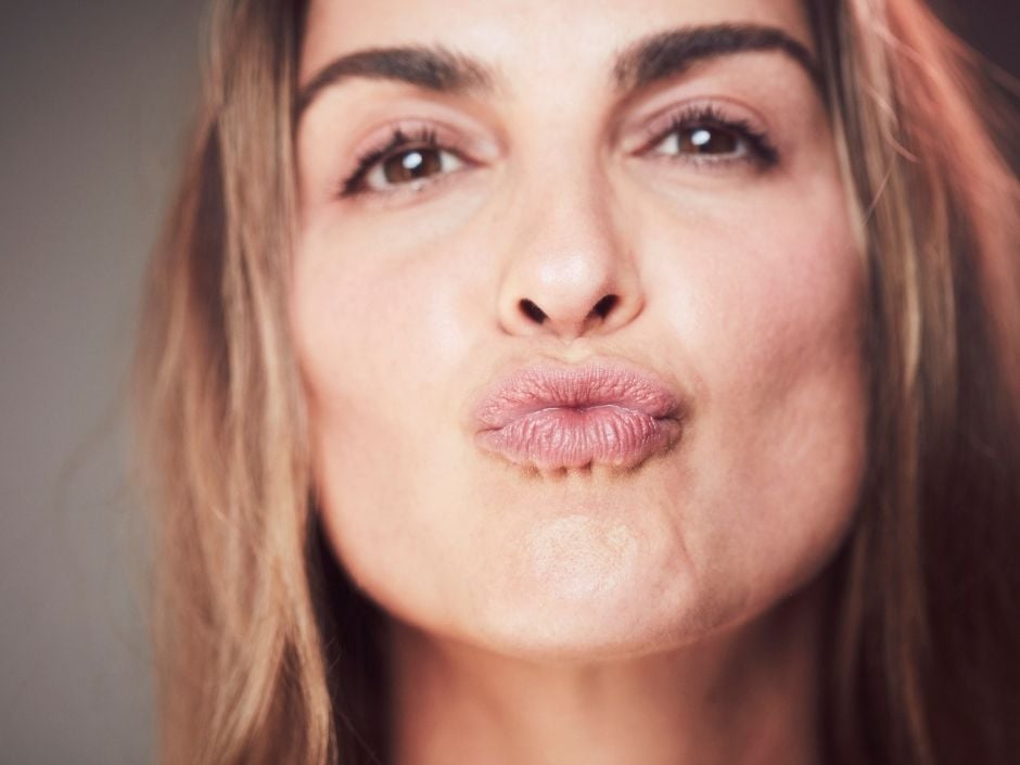 Woman looking into the camera and puckering her lips, ready to kiss