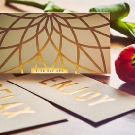 Gold-foil certificate for Viva Day Spa in Austin on a table with two envelopes which read 