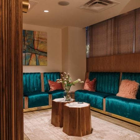 Med spa relaxation room with teal velvet booth seating with copper accent tables and colorful artwork at Viva Day Spa + Med Spa on South Lamar in Austin, TX