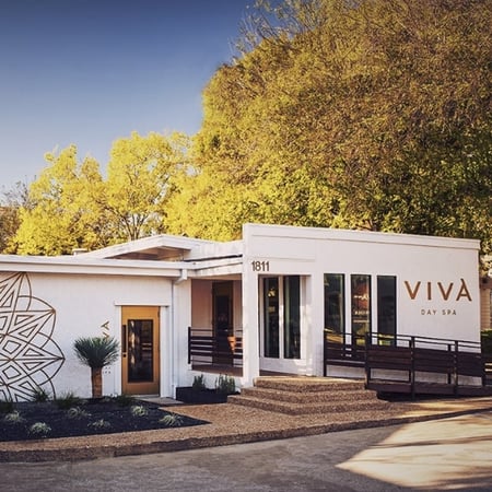 Exterior of Viva Day Spa + Med Spa on West 35th Street near Mopac in Central Austin, TX, a white building featuring a geometric mandala mural and mature shade trees