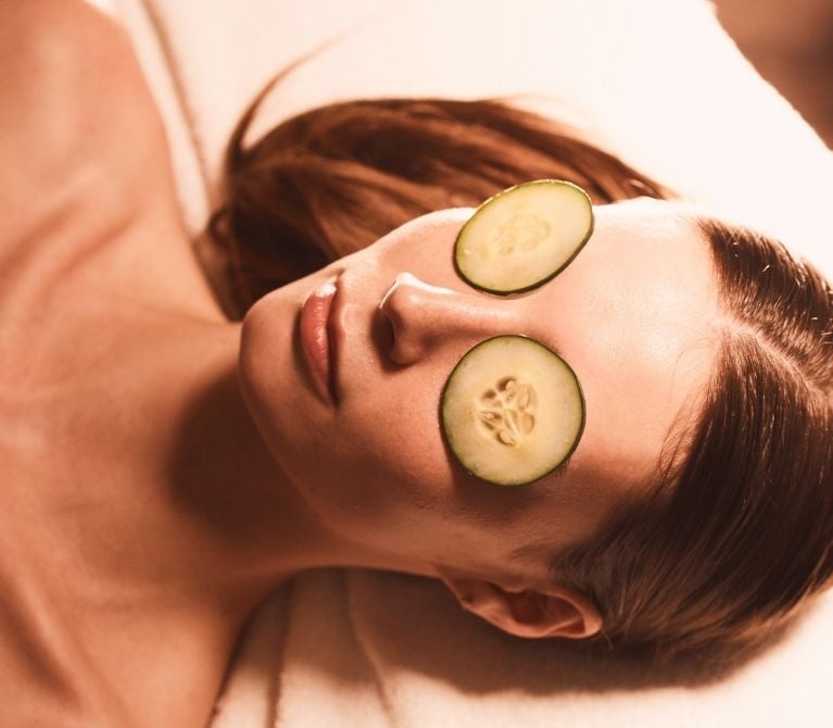 Close-up of a woman's face with fresh cucumber slices over her eyes at during a facial at Viva Day Spa + Med Spa