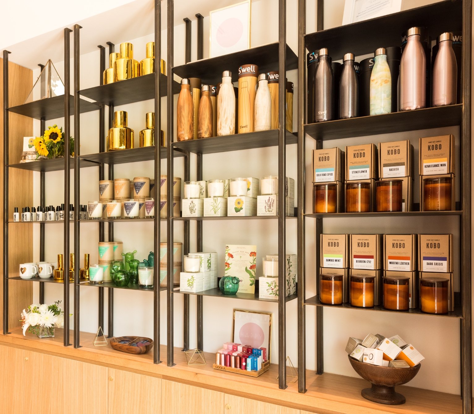 Retail boutique shelves displaying scented candles, water bottles and skincare products at Viva Day Spa + Med Spa