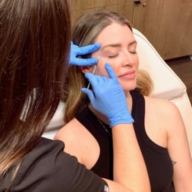 Woman receives cosmetic injectable, Botox, under the outer corner of her eyebrow at Viva Day Spa + Med Spa in Austin, Dallas, and Round Rock, TX.