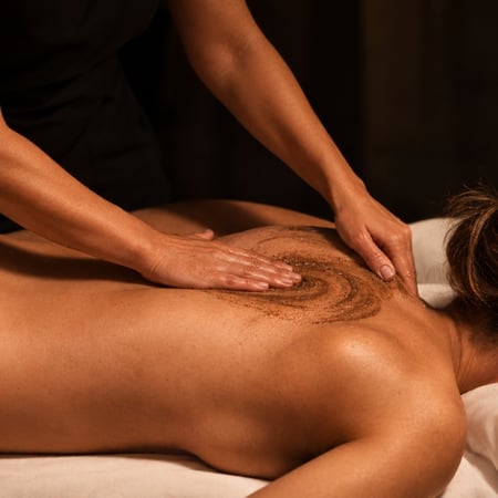 Woman on a spa table receiving a moor mud body scrub treatment at Viva Day Spa + Med Spa