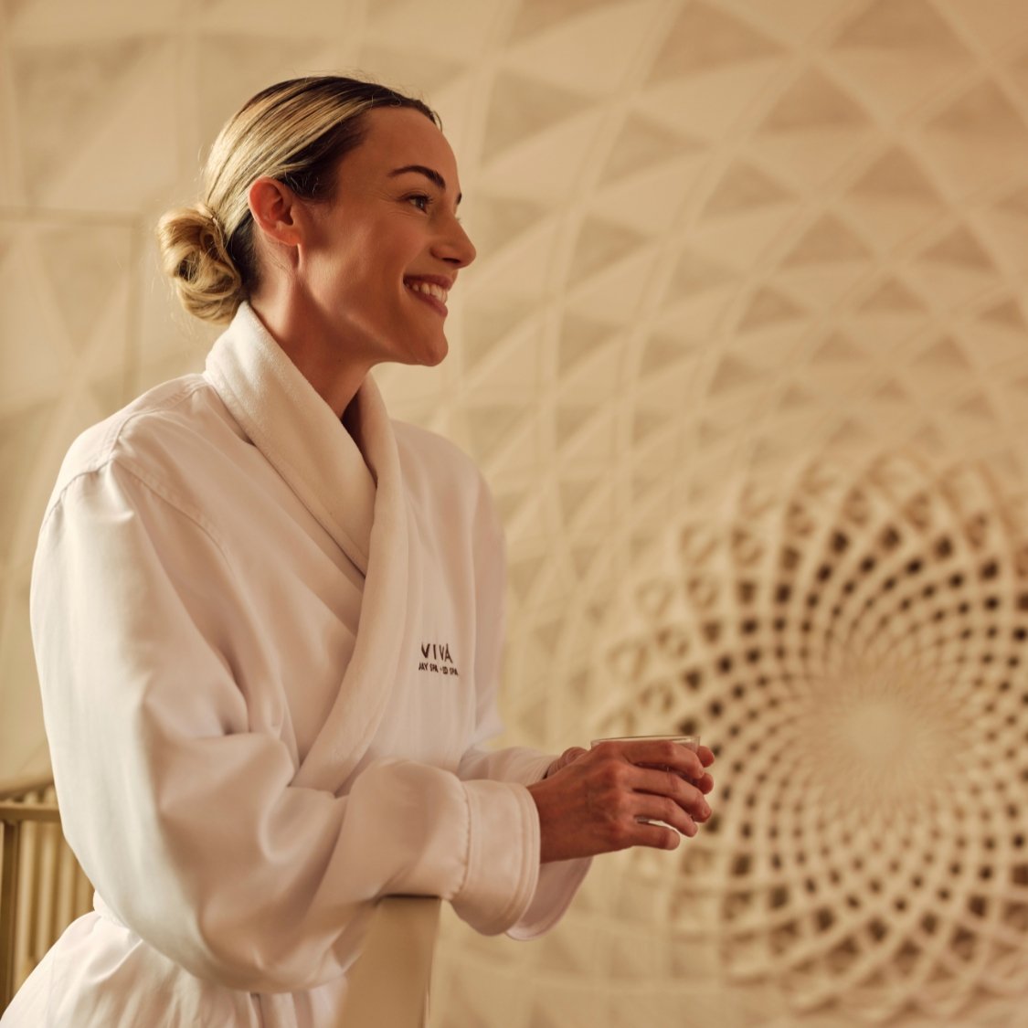 Woman in Viva Day Spa robe smiling and looking relaxed at Viva Day Spa.