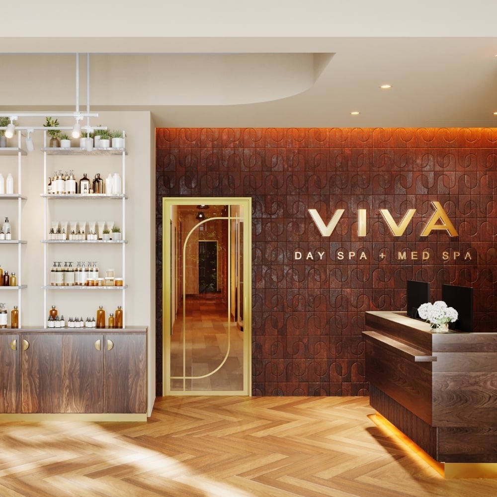 Architectural rendering of the lobby at Viva Day Spa + Med Spa Morningside opening January 2027 in Atlanta, GA, welcomes guests with warm wood finishes, a gold-framed glass door, and professional skin care product displays.